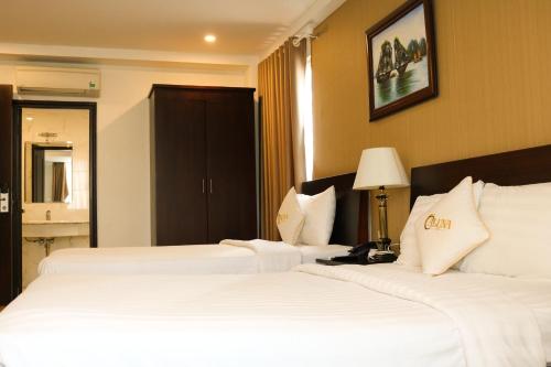 two beds in a hotel room with white sheets at ALUNA Ben Thanh Hotel in Ho Chi Minh City