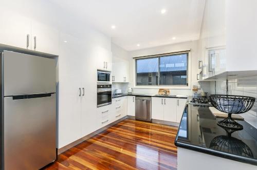 a kitchen with white cabinets and a stainless steel refrigerator at Shore Shanks in Port Fairy