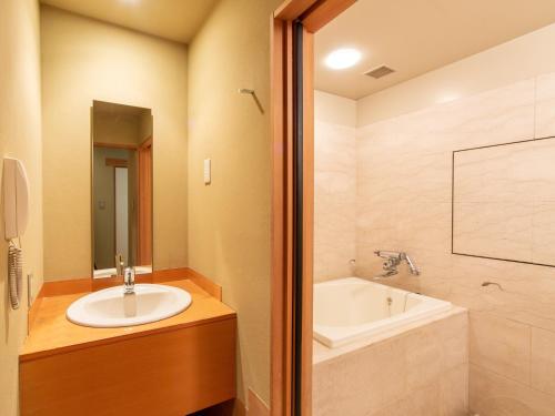a bathroom with a sink and a bath tub at Premier Hotel Mojiko in Kitakyushu