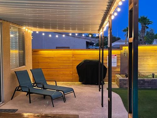 two chairs on a patio under a pergola with lights at Gorgeous Henderson Home with Pool! in Las Vegas