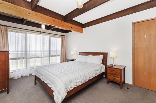 ein Schlafzimmer mit einem Bett und einem großen Fenster in der Unterkunft Swimmers Rest in Port Fairy