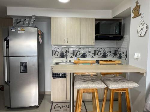 a kitchen with a stainless steel refrigerator and bar stools at New Lovely 3 bedroom condo with an AWESOME view! in Bello