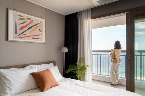 Una donna che guarda fuori dalla finestra di una stanza d'albergo di Urbanstay Sokcho beach C a Sokcho