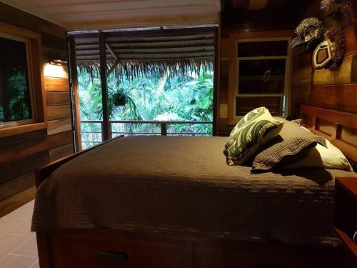 Schlafzimmer mit einem großen Bett und einem Fenster in der Unterkunft Cabina Harlequin at Margarita Hills Farm in Cocles