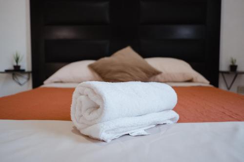 a stack of towels sitting on top of a bed at Casa LU~NA hermoso alojamiento en privada in Culiacán