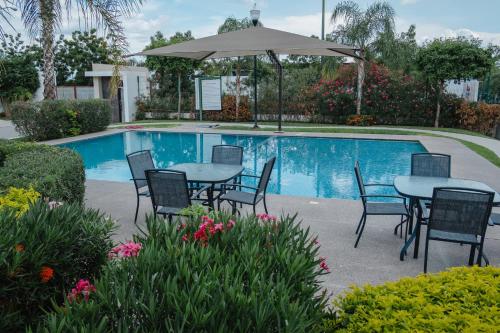 a patio with tables and chairs next to a pool at Casa LU~NA hermoso alojamiento en privada in Culiacán