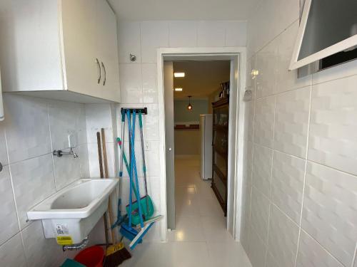 a white bathroom with a sink and a hallway at Apto com VISTA ESPETACULAR a BEIRA MAR no Pecado - Wi Fi 200 mb - 2 Quartos - Garagem - TV Smart - Piscina - Sauna - Ar condicionado - Portaria 24h - Churrasqueira - Cozinha equipada in Macaé