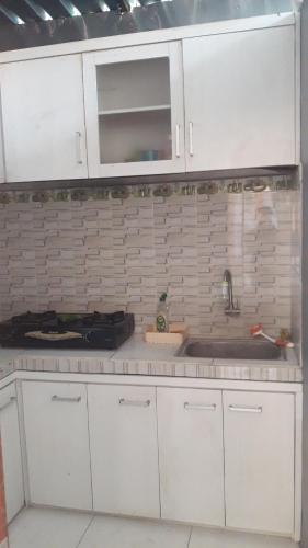 a kitchen with white cabinets and a sink at Sanata Yoga Guesthouse in Canggu