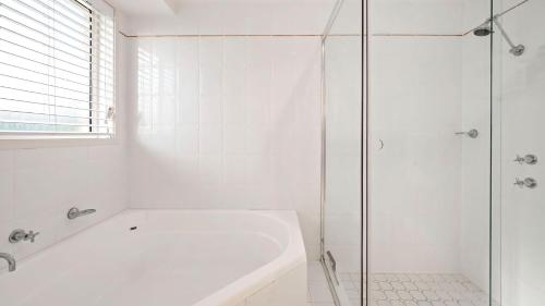 a white bathroom with a tub and a glass shower at My Shell Boat Harbour 55 Blanch Steet in Boat Harbour