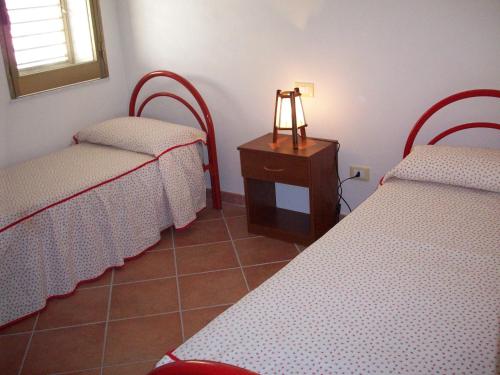 a room with two beds and a table with a lamp at Kalypso in Sciacca