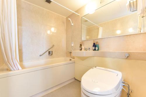 a bathroom with a toilet and a tub and a sink at Iki Marina Hotel in Iki