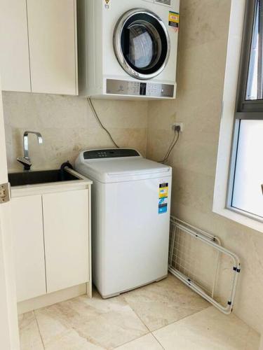 a laundry room with a washer and a washing machine at Beachfront apartment The Entrance Central Coast in The Entrance