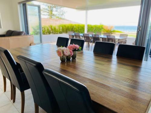 a large wooden table with chairs and flowers on it at Beachfront apartment The Entrance Central Coast in The Entrance