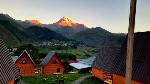 vista su una catena montuosa con case e montagne di Guesthouse Elli & Cottages a Kazbegi