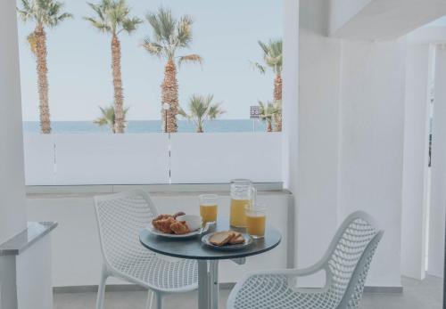una mesa con un plato de comida y dos vasos de zumo de naranja en Suitenes Coast en Rethymno Town