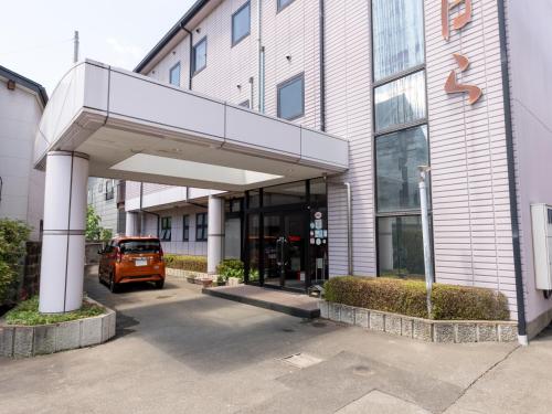 Tabist Business Ryokan Fukihara Ina Ihoku في Kinoshita: سيارة برتقالية متوقفة أمام مبنى