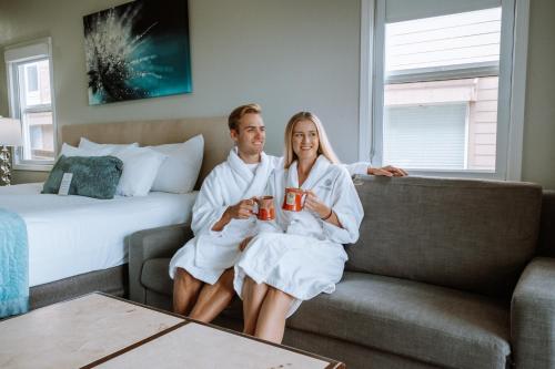 a man and woman sitting on a couch in a hotel room at Inn at the Prom Oceanfront in Seaside