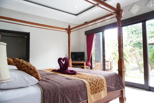 a bedroom with a canopy bed with a large window at Puri Bisma Ubud - 4 Bedroom PRIVATE VILLA - 10 min walking to Ubud Center in Ubud