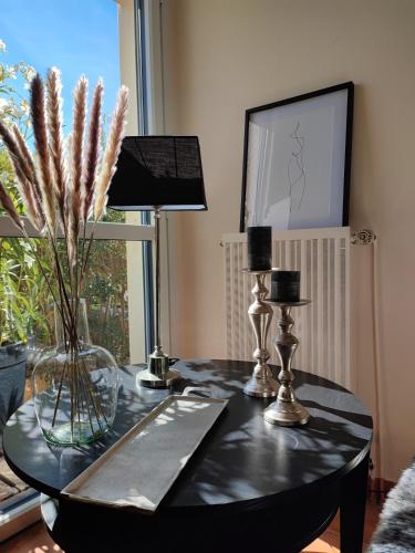 une table noire avec un vase de fleurs sur elle dans l'établissement Le 3 appartement vue mer avec jardin 100m de la plage et de la thalasso, à Concarneau