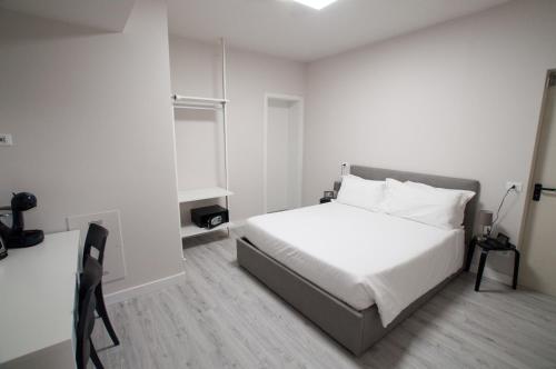 a white bedroom with a bed and a desk at Hotel Ca' di Gali in Sasso Marconi
