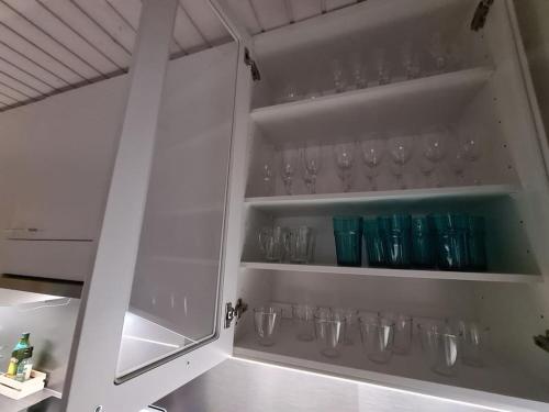 a white cabinet with glasses on the shelves at Villa Onia - sauna, palju ja iso yksityinen piha in Lappers