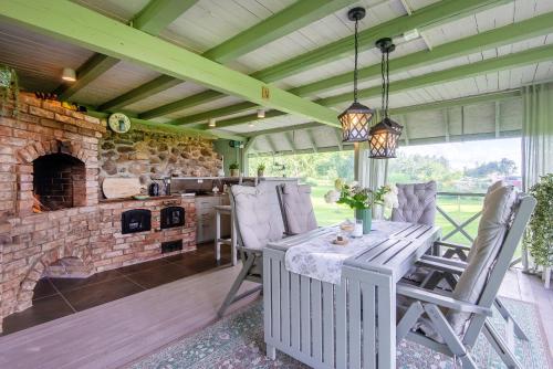 an outdoor kitchen with a stone fireplace and a table and chairs at Guest house Laimes taure in Vabole
