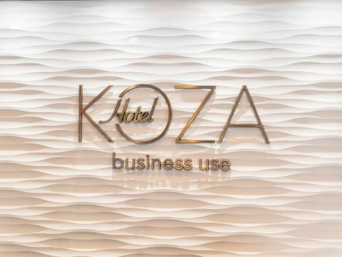 een bord voor een hotel of zakelijk gebruik op een achtergrond van golven bij Hotel Koza in Okinawa City