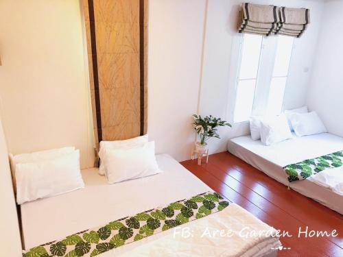 dwa łóżka w pokoju z dwoma oknami w obiekcie Aree Garden Home Private Homestay by the Waterfall Chantaburi - บ้านสวนพลิ้วอารี ริมธารน้ำตกพลิ้ว จันทบุรี 
