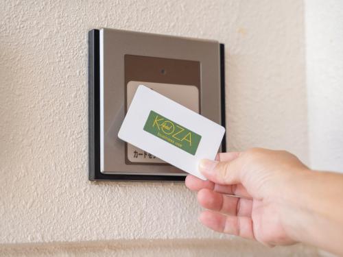uma pessoa com um cartão-chave num interruptor de luz em Hotel Koza em Okinawa City