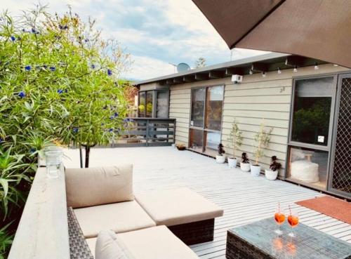a patio with a couch and a table and trees at Modern Beach House -Large Entertainers Deck ,Wineries, Hot Springs and Golf in Rye