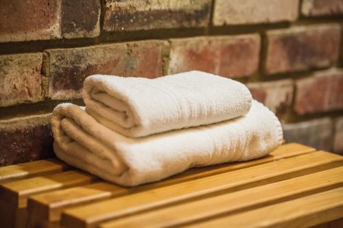 una pila de toallas sentadas en una mesa junto a una pared de ladrillo en Acacia Guesthouse Klerksdorp en Klerksdorp