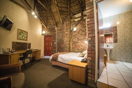 - une chambre avec un lit et un mur en briques dans l'établissement Acacia Guesthouse Klerksdorp, à Klerksdorp