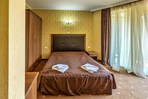 1 dormitorio con 1 cama con 2 toallas en Хотел Магнолия, Hotel Magnoliya, en Panichishte