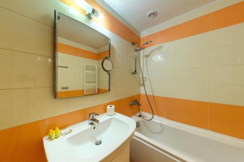 La salle de bains est pourvue d'un lavabo, d'un miroir et d'une baignoire. dans l'établissement Хотел Магнолия, Hotel Magnoliya, à Panichishte
