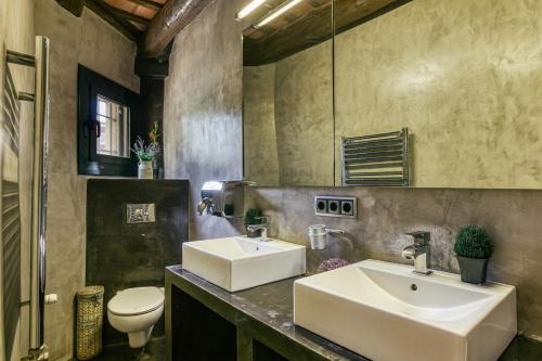 łazienka z 2 umywalkami i toaletą w obiekcie El paller w mieście Borrassá