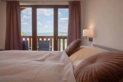 Tri Duby Golf Apartments في Badín: غرفة نوم بسرير ونافذة كبيرة