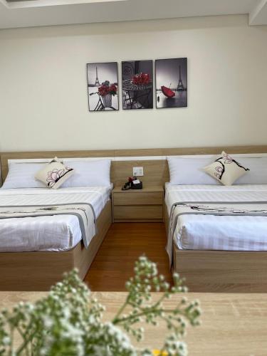 two beds in a room with three pictures on the wall at Khách sạn Khang An Buôn Ma Thuột in Buon Ma Thuot