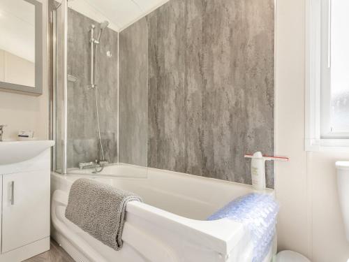 W łazience znajduje się biała wanna i prysznic. w obiekcie The Cotswold Holiday Lodge w mieście Evesham