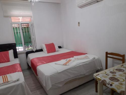 a bedroom with two beds with red and white sheets at ERAY PANSİYON in Gokceada Town