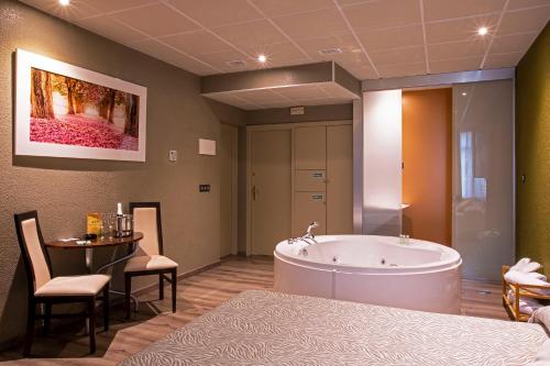 La grande salle de bains est pourvue d'une baignoire, d'une table et de chaises. dans l'établissement Motel Los Abedules, à Oviedo