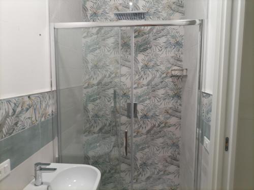 una ducha con una puerta de cristal junto a un lavabo en Sabbiad'oro, en Santa Maria del Focallo