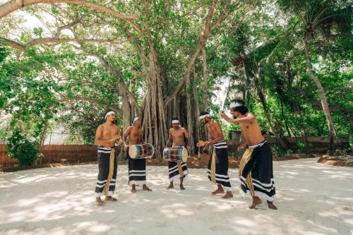 a group of men playing drums in front of trees at Nova Maldives in Dhangethi