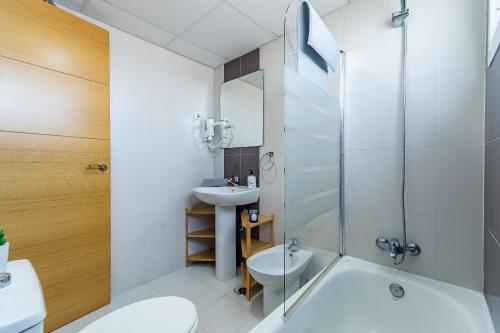 a bathroom with a sink and a tub and a toilet at Valparaiso Premium Playa Apartment with parking in Málaga
