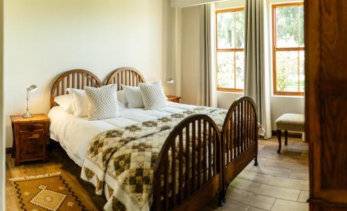 ein Schlafzimmer mit einem großen Bett und zwei Fenstern in der Unterkunft Baris Guesthouse in Clarens