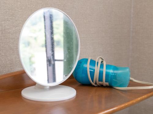 a mirror on a table next to a blue cup at Tabist Izumi Yusen Shukuhaku Center in Izumi