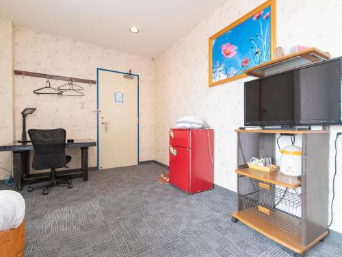 a room with a desk and a red refrigerator at Tabist Izumi Yusen Shukuhaku Center in Izumi