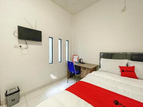a bedroom with a bed and a desk and a tv at RedDoorz Syariah near Siloam Hospital Mataram in Mataram