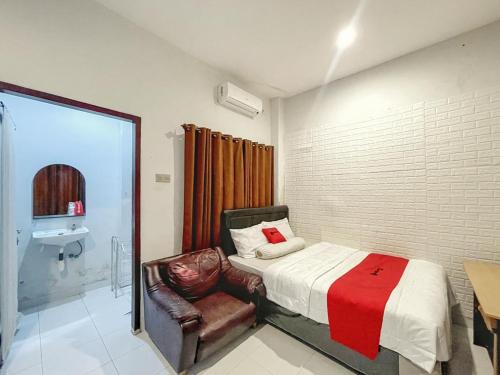 a bedroom with a bed and a chair and a sink at RedDoorz Syariah near Siloam Hospital Mataram in Mataram