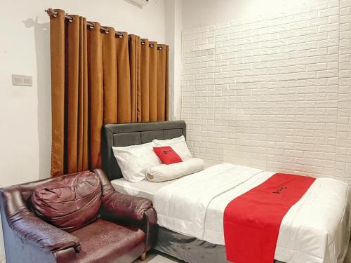 a bedroom with a bed and a chair with a red pillow at RedDoorz Syariah near Siloam Hospital Mataram in Mataram