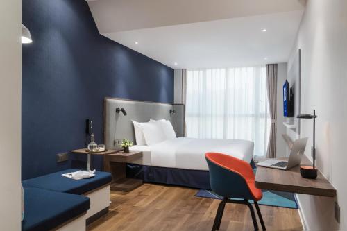um quarto de hotel com uma cama, uma secretária e uma cadeira em Holiday Inn Express Foshan Chancheng, an IHG Hotel em Foshan